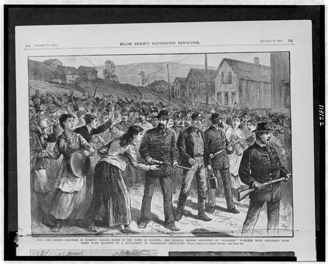 Illustration of working miners returning home from work, accompanied by gun-toting Pinterton Detective Agents, passing by enraged striking miners.